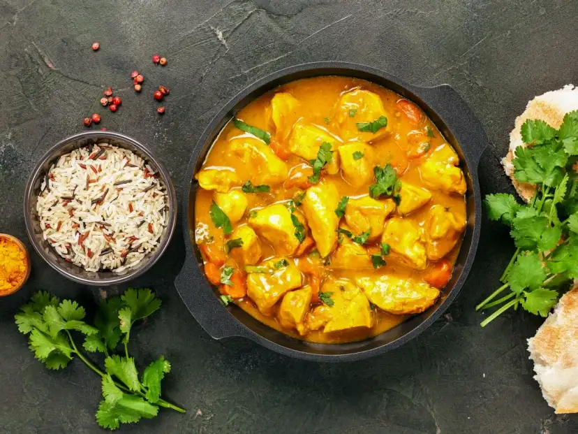 Kurczak w sosie curry z ryżem, kolendrą i pieczywem.