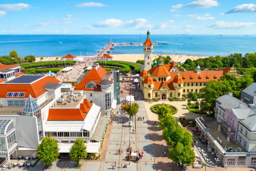 Widok z lotu ptaka na nadmorską miejscowość z plażą, molo i zabytkowymi budynkami.