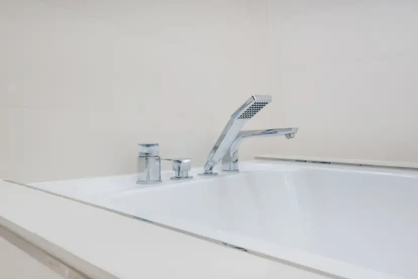 Elegancka bateria wannowa jednootworowa z chromowanymi elementami i słuchawką prysznicową, idealna do nowoczesnej łazienki.
