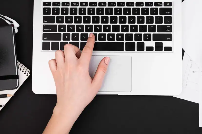 Dłoń naciska klawisz "C" na klawiaturze laptopa, co może być przyczyną, dlaczego nie działa klawiatura w laptopie.