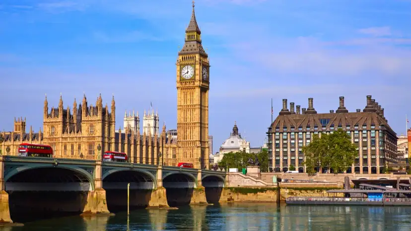 Big Ben Londyn z czerwonymi autobusami na moście i rzeką w tle.