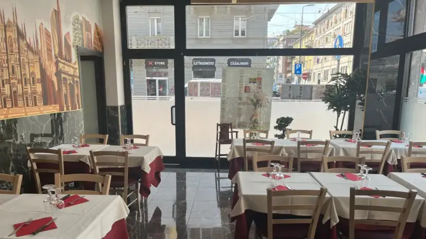 Restaurant interior with tables set for dining, featuring a mural of Milan's skyline.