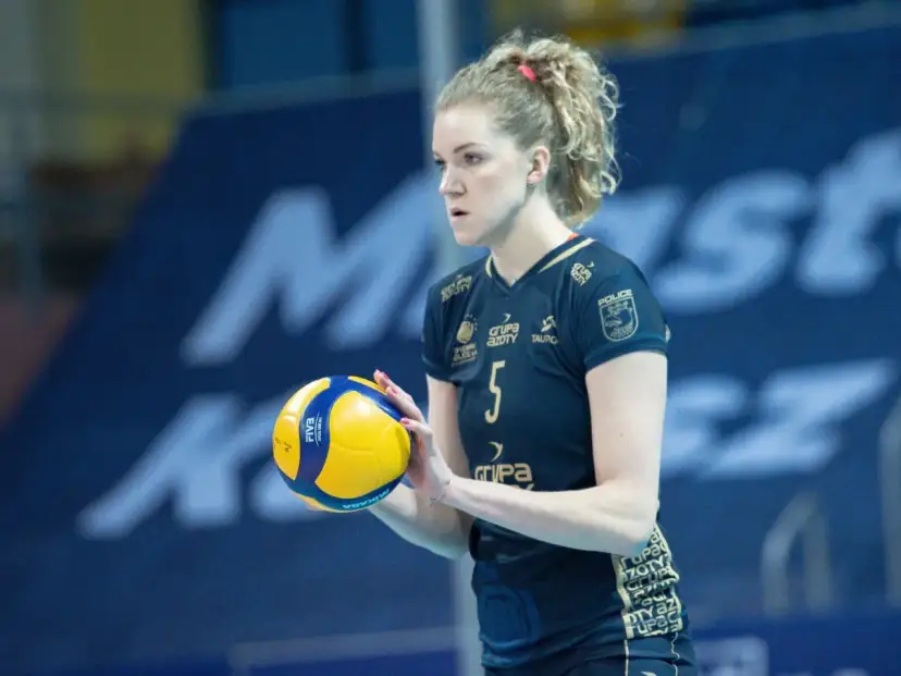 Agnieszka Korneluk, siatkarka z numerem 5, trzyma piłkę. Jej mąż pewnie kibicuje jej z trybun.