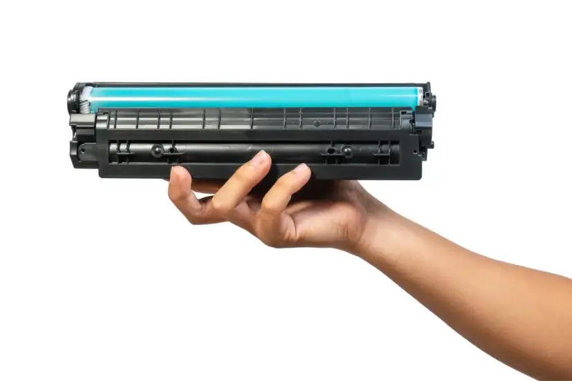 Dłoń trzymająca toner do drukarki HP. Dowiedz się, jak wymienić tusz w drukarce HP, aby cieszyć się wydrukami.