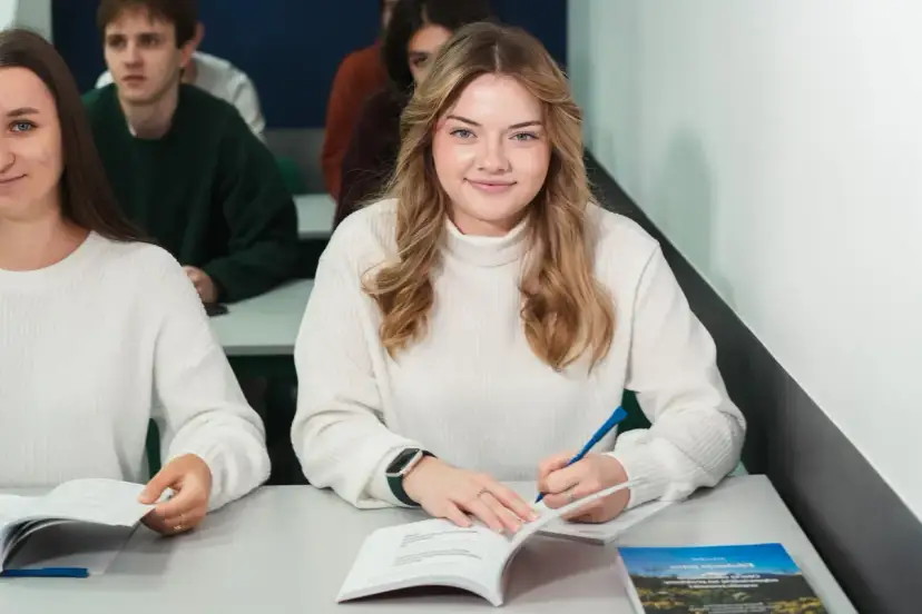 Uśmiechnięta studentka pisze w zeszycie, idealne zdjęcie do legitymacji.