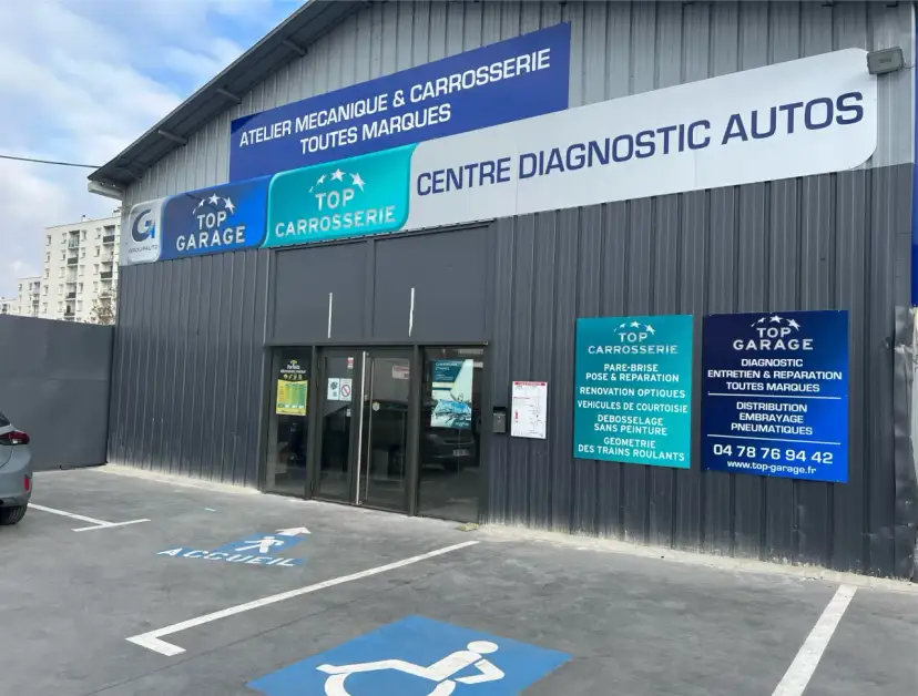 Façade d'un centre automobile avec des panneaux "Top Garage", "Top Carrosserie" et "Centre Diagnostic Autos".