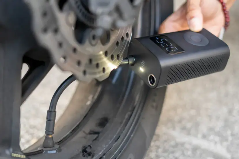 Gonfleur de pneu sans fil connecté à la valve d'une roue de moto, affichant la pression.