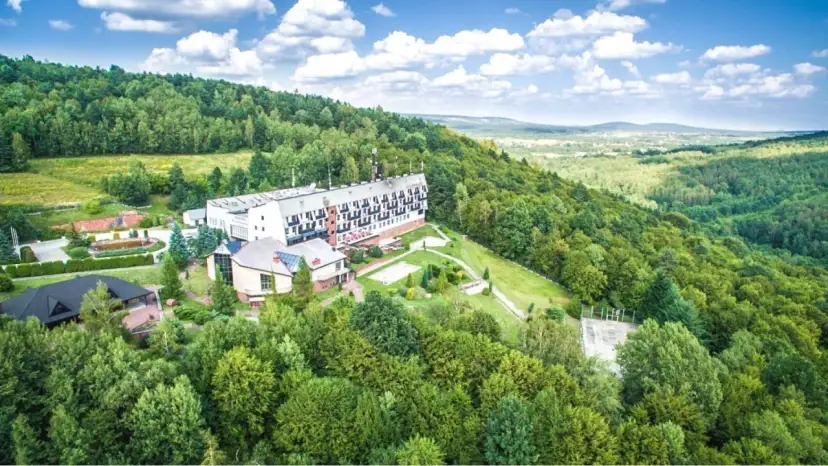 Hotel w otoczeniu zielonych lasów Gór Świętokrzyskich, z widokiem na dolinę.