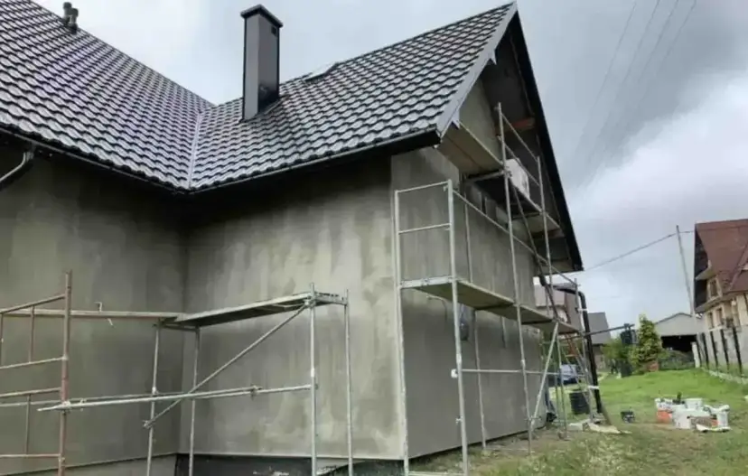 Dom w trakcie ocieplania elewacji i dachu, z rusztowaniami.