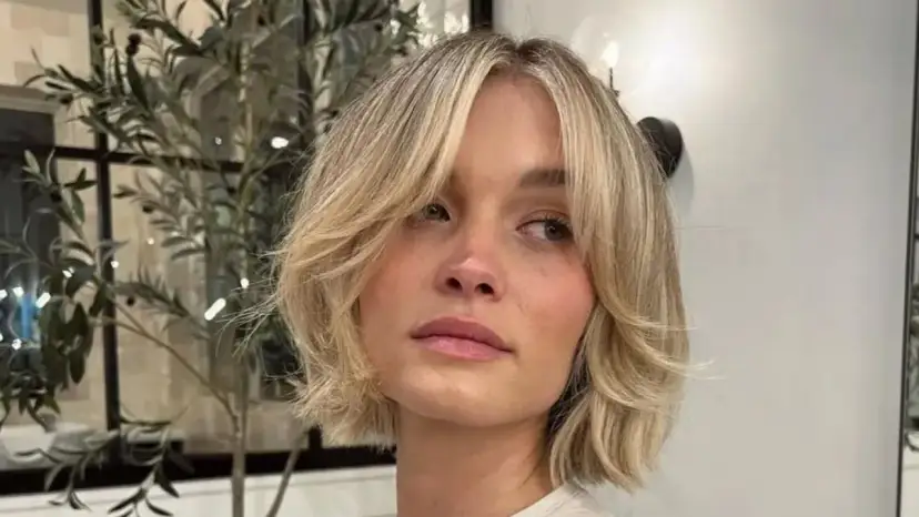 Kobieta z blond włosami w stylu cienkie włosy bob warstwowy cieniowany, z delikatnymi falami i grzywką na bok.