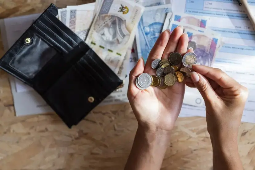 Dłonie liczą monety i banknoty obok otwartego portfela. Szybka, bezpieczna chwilówka to rozwiązanie, gdy brakuje gotówki.