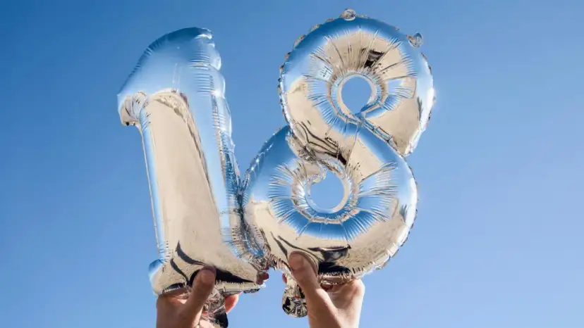 Silberne Folienballons in Form der Zahl 18 vor blauem Himmel.