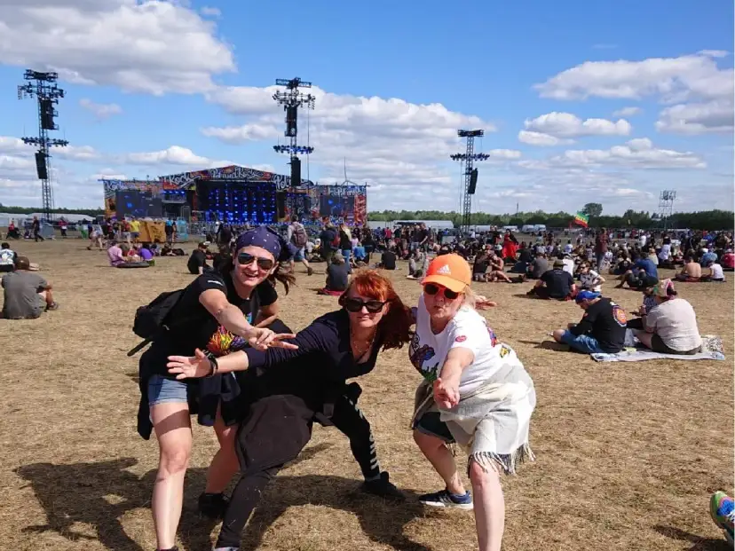 Trzy kobiety bawią się na festiwalu czaplinek pol and rock. W tle scena i tłum ludzi.
