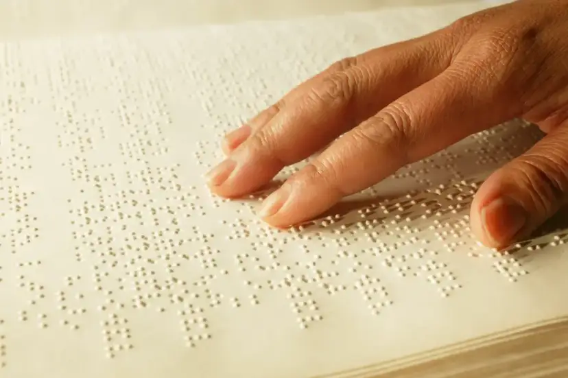 Dłoń czytająca tekst w alfabecie Braille'a.
