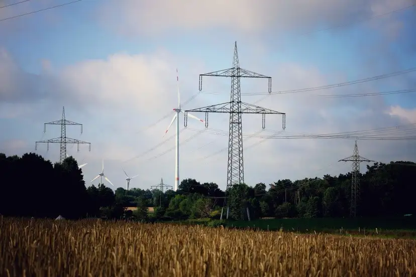 Wiatraki i linie energetyczne na tle nieba. OZE w Polsce to przyszłość, która już dziś zasila nasze domy.