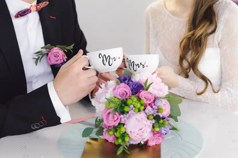 Para świętuje 4 rocznicę ślubu, trzymając kubki "Mr." i "Mrs." na tle bukietu kwiatów.