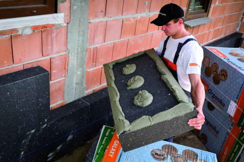 Budowlaniec przygotowuje się do montażu, kiedy kołkować styropian. Klej na płycie izolacyjnej.
