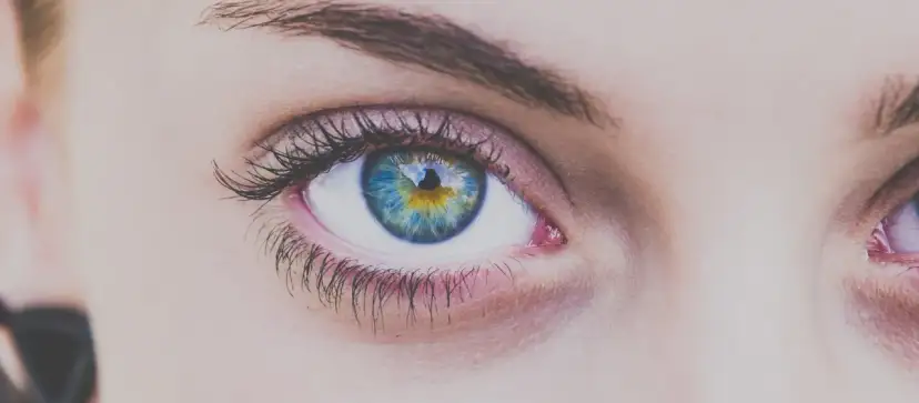 Zbliżenie na niebiesko-zielone oko z odbiciem w źrenicy.