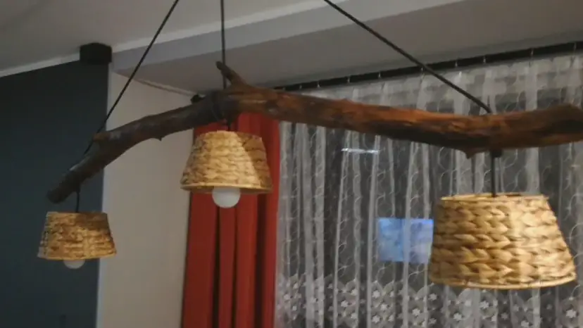 Jak odnowić stary drewniany żyrandol? Ta rustykalna lampa z gałęzi i plecionych kloszy z pewnością doda uroku wnętrzu.