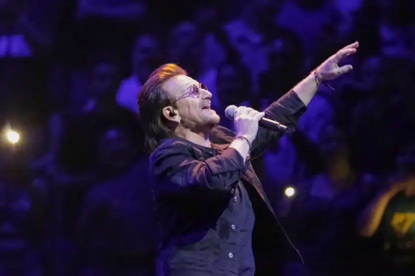 Bono z U2 śpiewa na koncercie, zapowiadając u2 nowa płyta. Tłum w ciemnościach reaguje na jego występ.