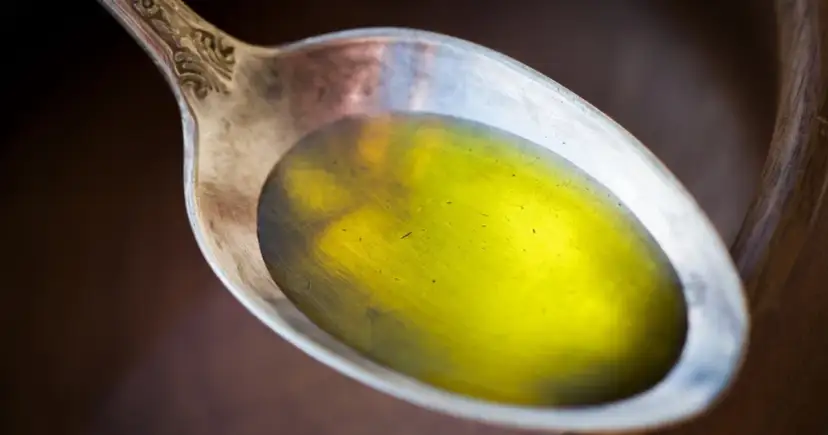 Łyżka z płynnym, żółtym olejem lnianym, który może pomóc w obniżeniu cholesterolu.