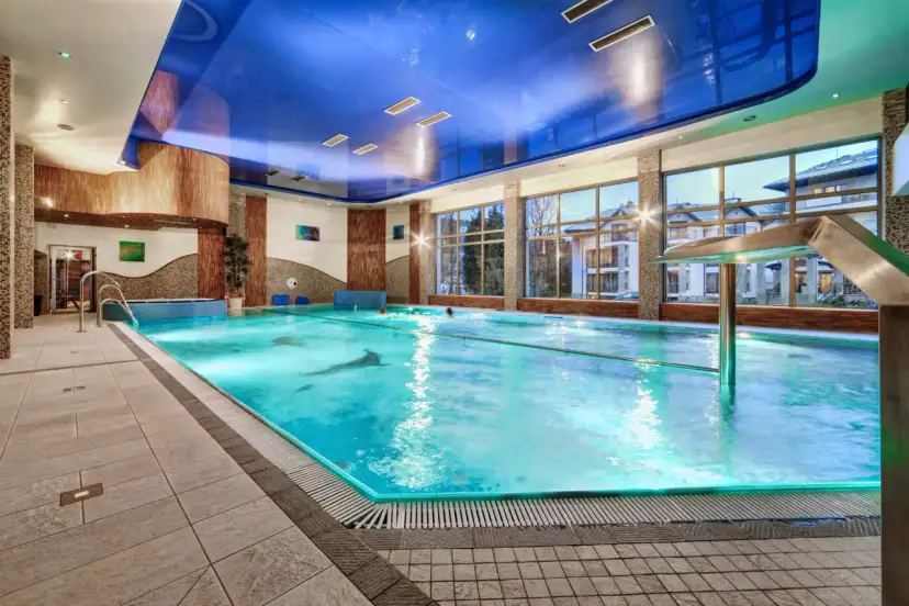Basen w hotelu dla dorosłych Polska. Błękitna woda, nowoczesny design, okna z widokiem na budynki.