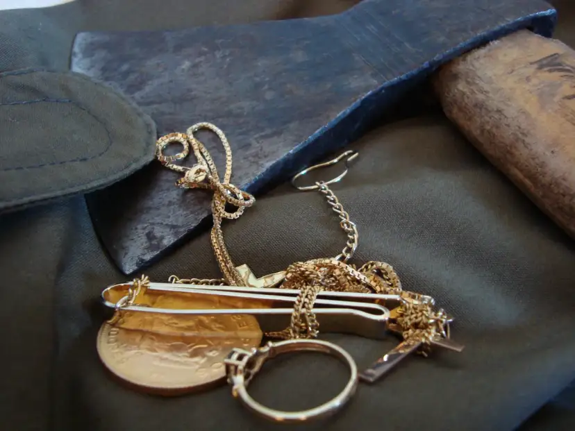 Zbrodnia i kara epoka: siekiera, złoty łańcuszek, moneta i pierścionek na ciemnym tle.