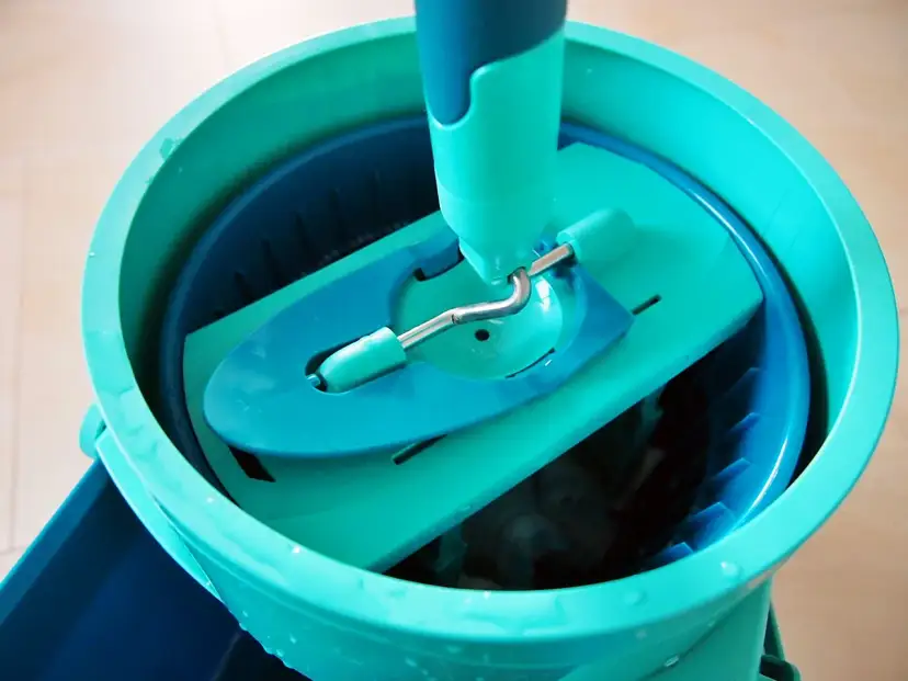 Turkusowe wiadro z obrotowym mopem i systemem odciskania.