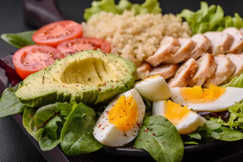 Sałatka z kurczakiem, awokado, jajkiem i pomidorami. Czy ketoza jest zdrowa? Taki posiłek może być częścią diety ketogenicznej.