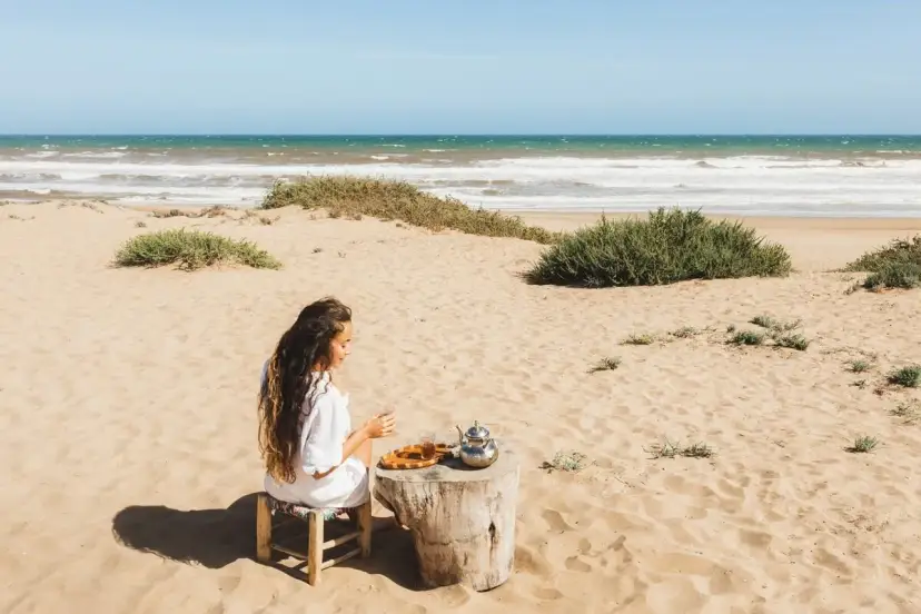 Kobieta pije herbatę na plaży, delektując się spokojem. To jedno z tunezja najpiękniejsze miejsca, gdzie czas płynie wolniej.