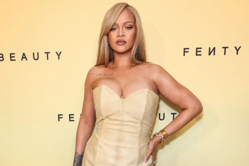 Rihanna w beżowej sukni, prezentuje modny kolor. Tło z logo Fenty Beauty.