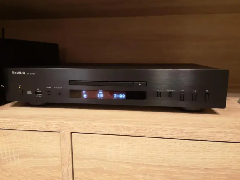 Czarny odtwarzacz CD Yamaha CD-S303 na drewnianej półce, gotowy do testu. Wyświetlacz pokazuje utwór 10 z 2:08.