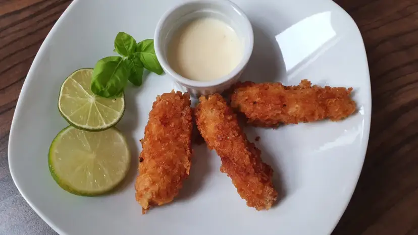 Chrupiąca ryba w panko, podana z sosem i limonką, wygląda apetycznie.
