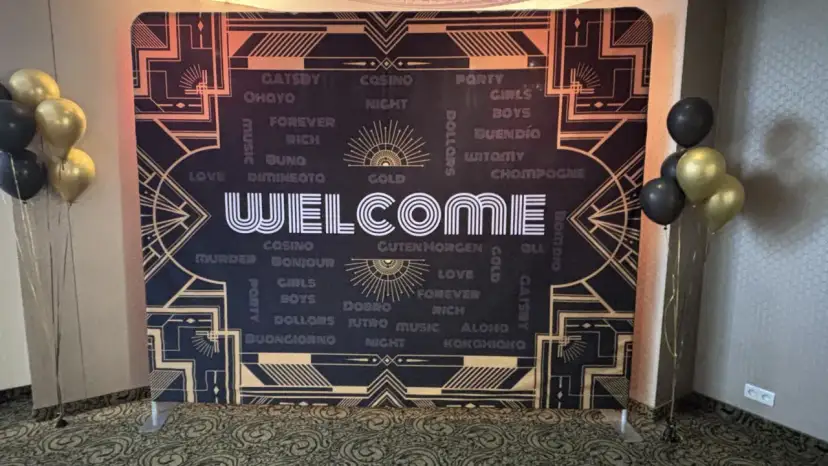 Tło w stylu lat 20. z napisem "WELCOME" i złotymi balonami.