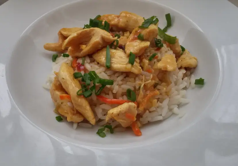 Pyszny kurczak marynowany w sosie sojowym z ryżem i warzywami, posypany szczypiorkiem.