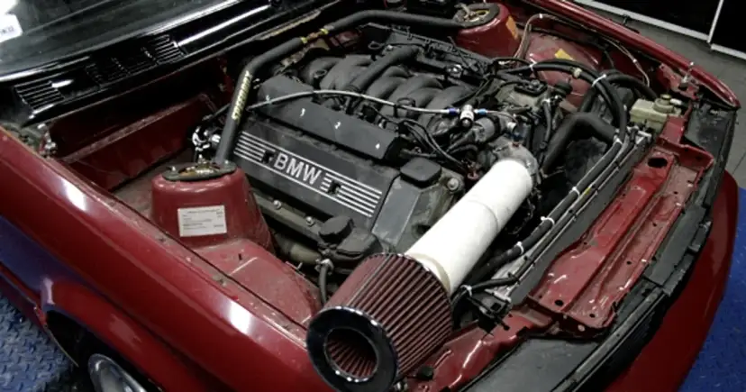 Czerwony silnik BMW z widocznym filtrem powietrza i elementami tuningu.