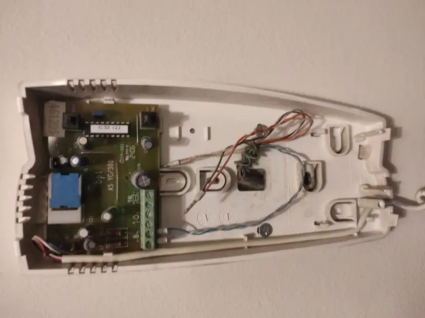 Wnętrze domofonu z widoczną płytką drukowaną i przewodami.