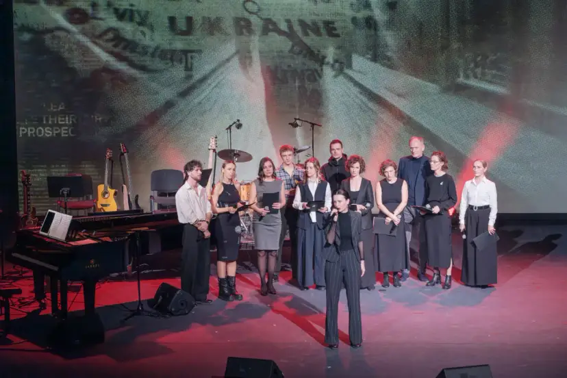 Grupa artystów na scenie, gdzie odbywa się koncert dla Ukrainy. W tle ekran z napisem "UKRAINE".