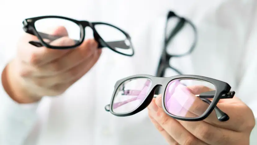 Dłonie trzymające czarne okulary korekcyjne.