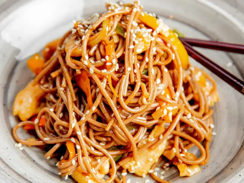 Soba z kurczakiem i warzywami, posypana sezamem. Pyszny przepis na soba, idealny na szybki obiad.
