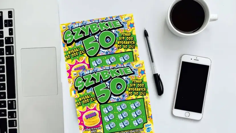 Dwie zdrapki "Szybkie 50" leżą obok laptopa, telefonu i kawy. Czyżby zdrapka jest wygrana?