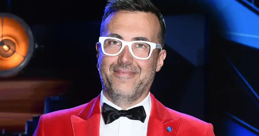 DJ z "Jaka to melodia?" w czerwonej marynarce i białych okularach, gotowy do zabawy.