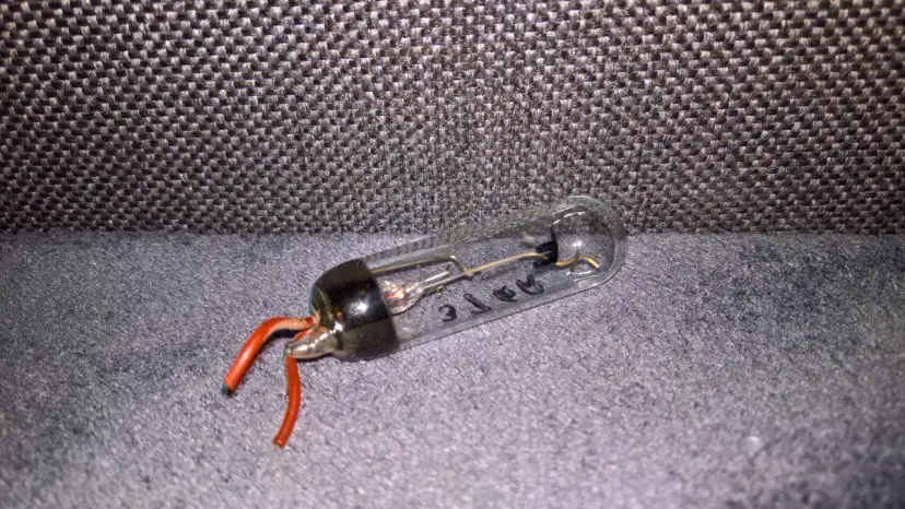 Szklana bańka z elementami elektronicznymi i czerwonymi przewodami. Tak wygląda prostownik, który kiedyś zasilał urządzenia.