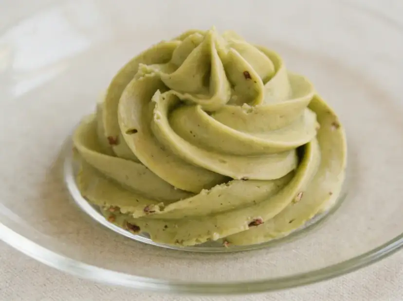 Puszysty krem pistacjowy do tortu, udekorowany na talerzyku.