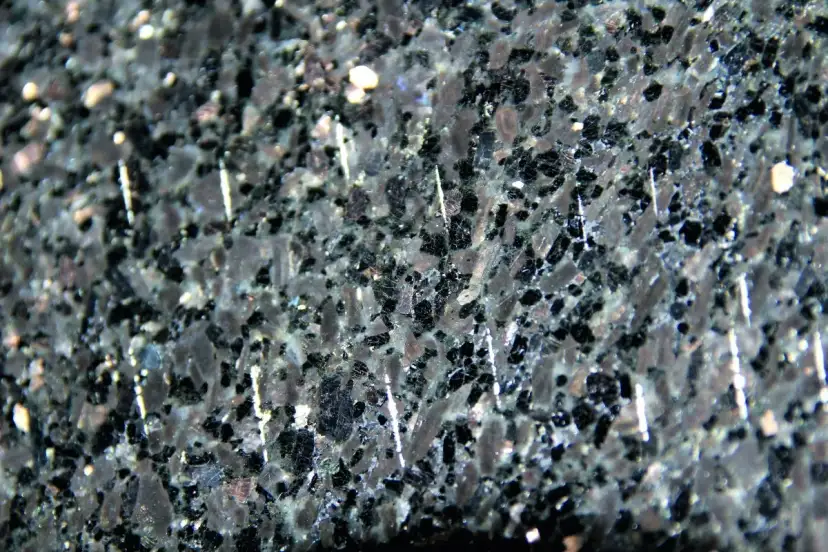 Zbliżenie na ciemny, granitowy blat kuchenny z widocznymi białymi, pionowymi rysami.