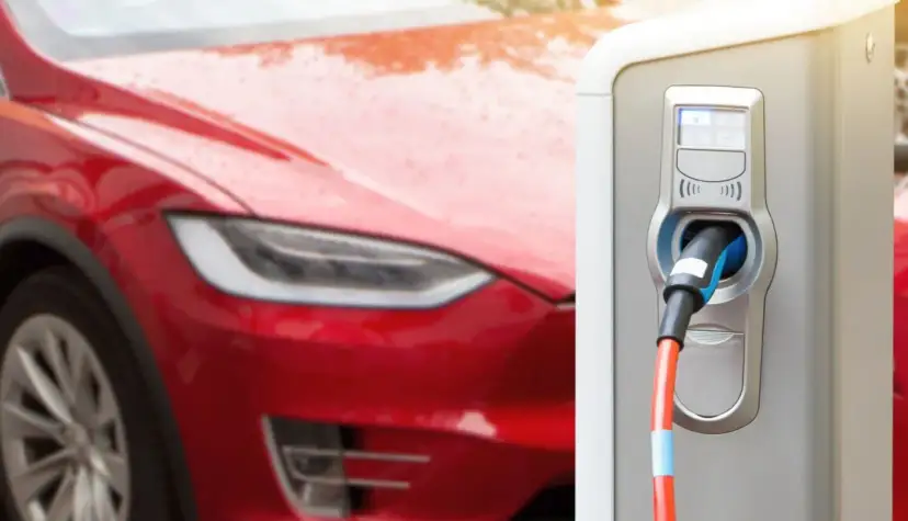 Czerwona Tesla podłączona do ładowarki elektrycznej.