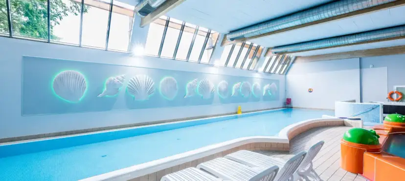 Basen w hotelu z dekoracjami muszli i leżakami. Idealne miejsce na relaks, jak w najlepszych hotelach nad morzem z pełnym wyżywieniem.