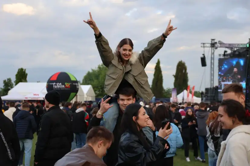 Dziewczyna na ramionach chłopaka cieszy się na Juwenaliach Politechniki Lubelskiej. W tle scena i tłum bawiących się studentów.
