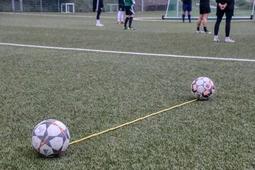 Dwa piłki na boisku połączone żółtą linką. Trening, który pokazuje, jak nie być profesjonalnym piłkarzem.