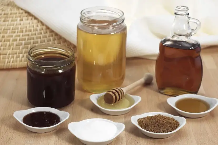 Domowy syrop cukrowy i kupny syrop barmański obok miodu i cukru.